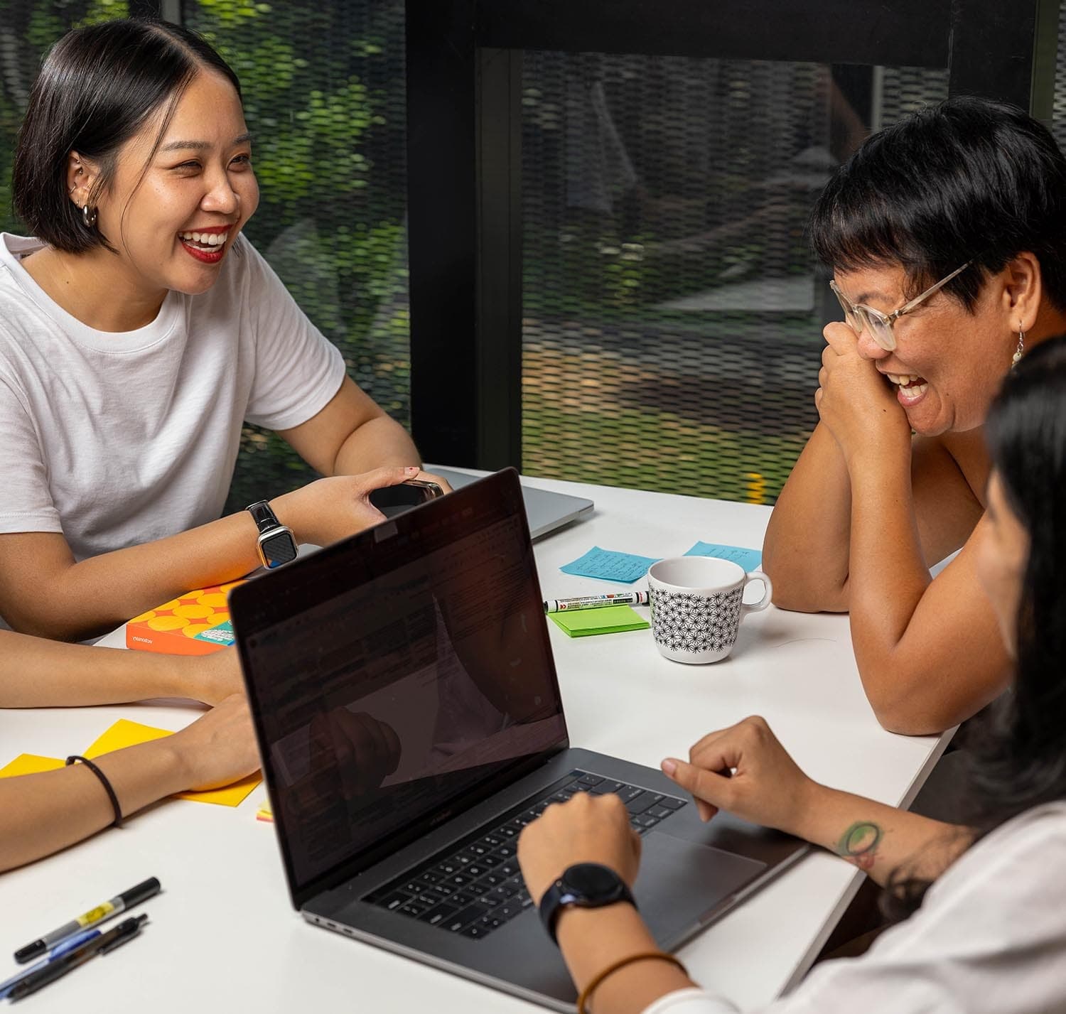 Team members in a group discussion with a laptop on a table