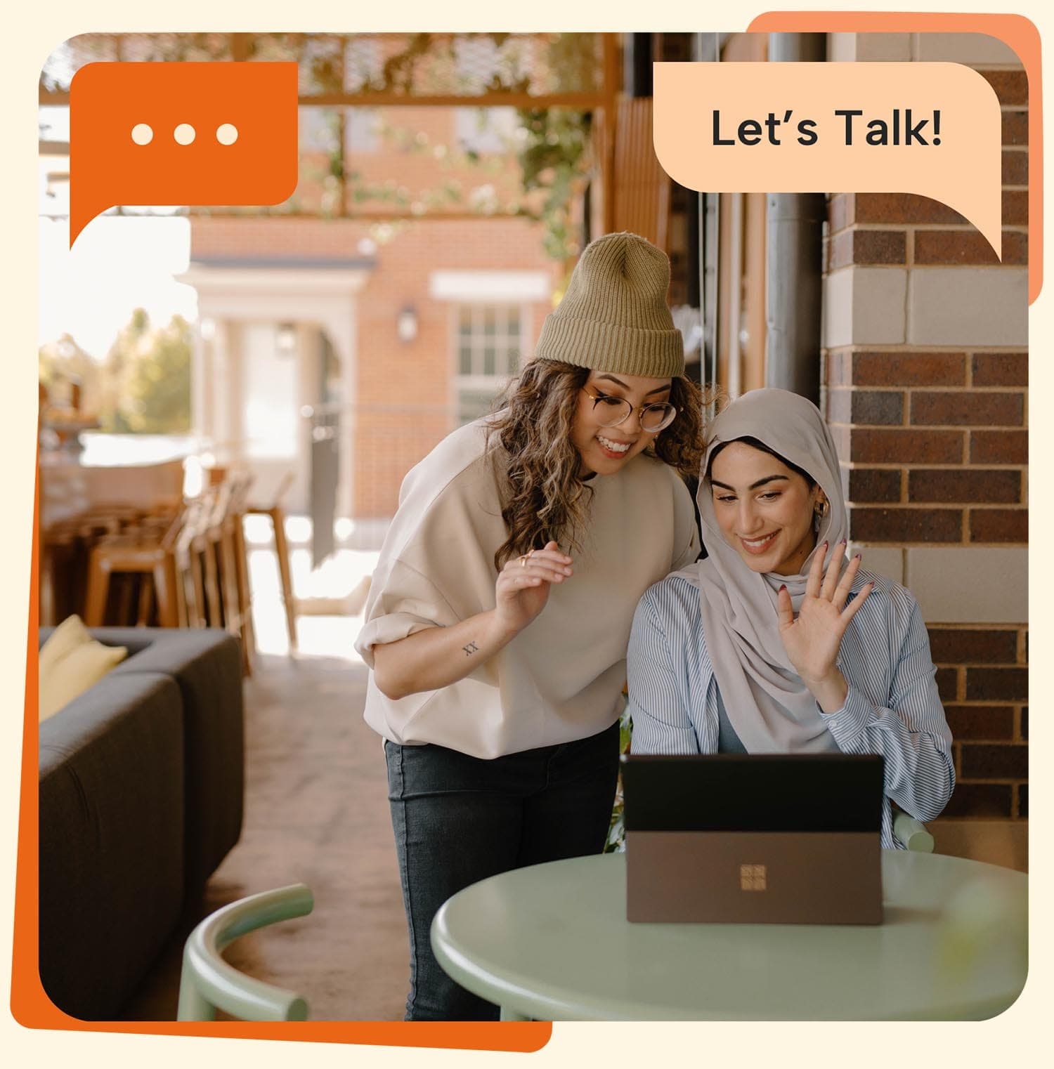 Two people sitting outdoors using a laptop during a conversation