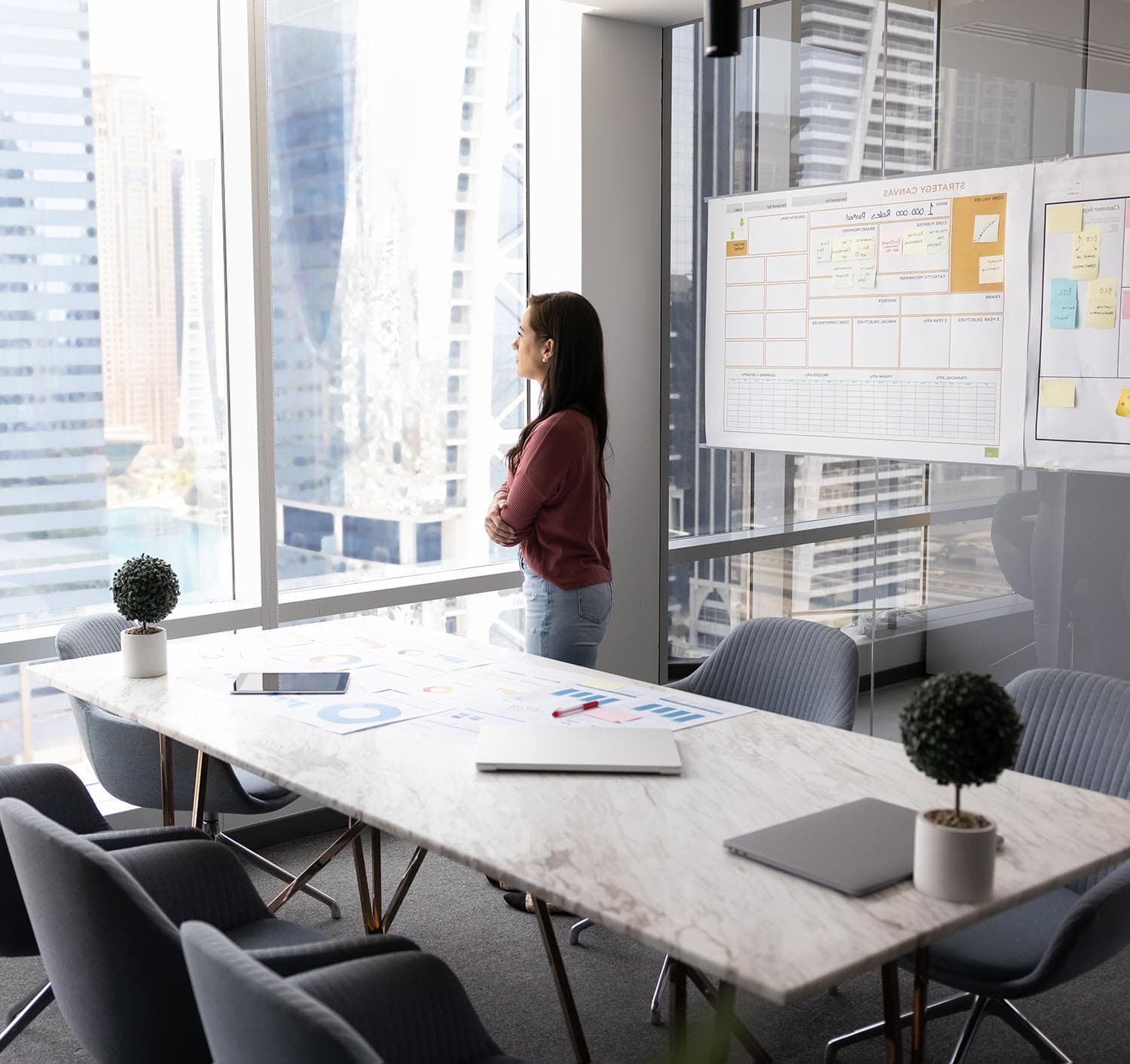 Person standing by a window in an office looking outside in contemplation