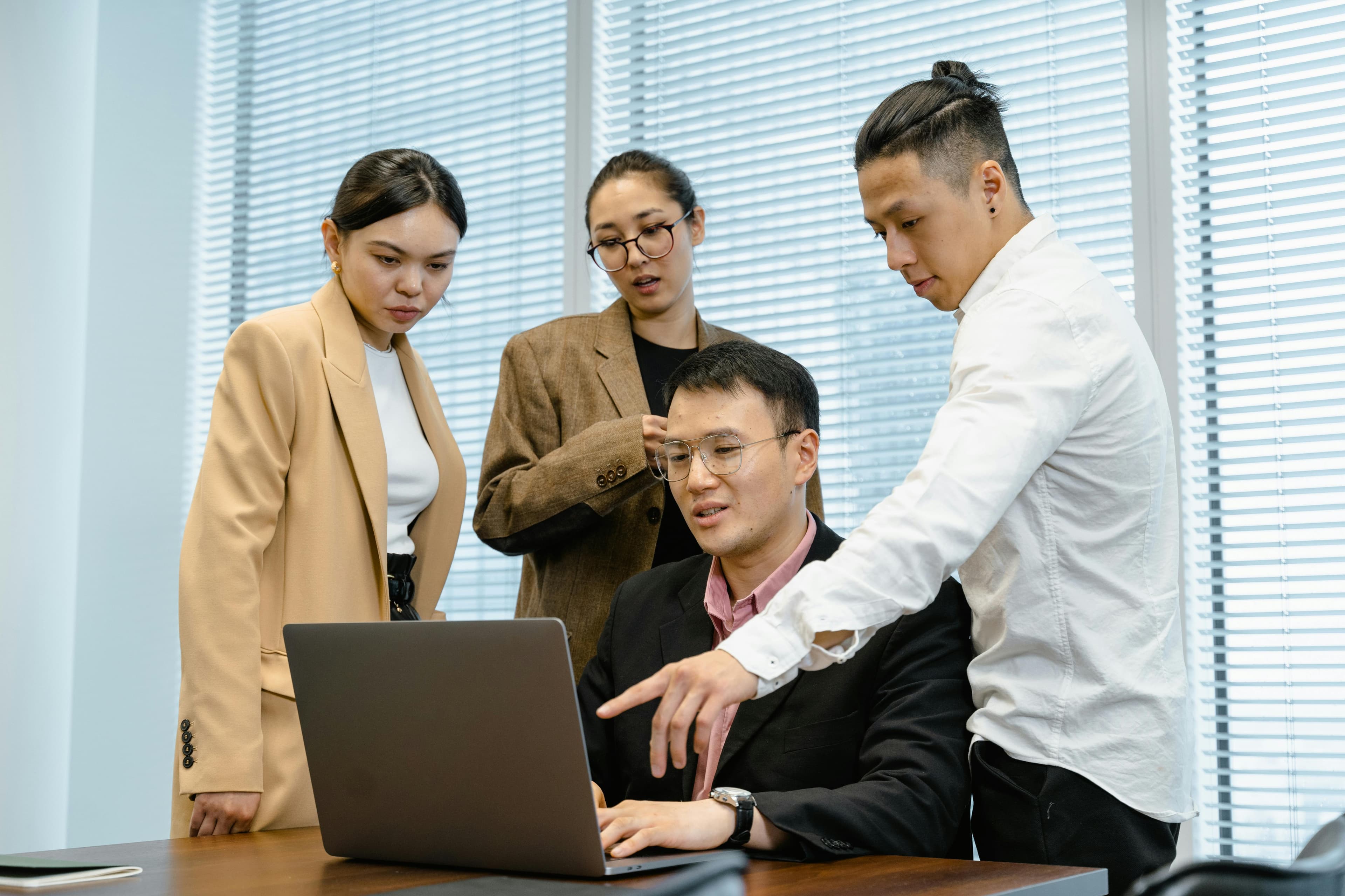 Group of people gathered around a laptop reviewing information together